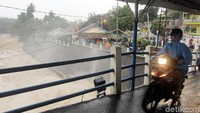 Pengendara melintas di jembatan pintu air Bendung Katulampa yang kini masih berstatus siaga II.