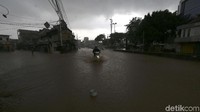 Jalan raya terendam hingga 50 cm. Sementara langit mendung masih mengelayut.