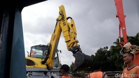 Petugas kebersihan Pemprov DKI Jakarta membantu mengangkat material sampah berupa kayu ke badan jalan.