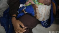 Bayi Khaidar tampak tertidur pulas di pangkuan ibunya. Ia lahir normal dengan bantuan bidan, namun akta kelahirannya masih ditahan karena belum dapat melunasi biaya persalinan. Foto: Agung Pambudhy/detikHealth  