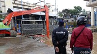 Alat berat mengangkat sampah yang menyangkut di pintu air.