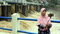 Seorang warga selfie dengan latar belakang pintu air Bendung Katulampa.