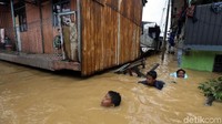 Anak-anak bermain di tengah banjir.
