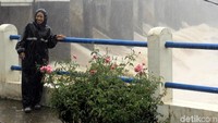 Meski hujan, warga tetap nekat berfoto-foto dengan latar belakang pintu air Bendung Katulampa dengan aliran air yang deras.