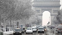 Aktvitas lalu lintas terlihat padat di Champs-Elysees, dekat Arc de Triomphe. Jarak pandang sedikit terganggu akibat salju lebat yang turun. Foto: REUTERS/Charles Platiau