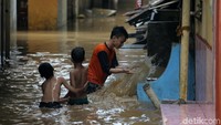 Beberapa bocah tampak asyik bermain di tengah banjir.