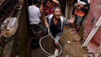 Seorang warga terlihat sangat semringah saat berhasil menangkap ikan di tengah banjir.
