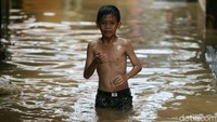 Seorang bocah melintasi banjir di kawasan permukiman warga di Kebon Pala, Kampung Melayu, Jakarta Timur, Rabu (7/2/2018).