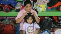 Pengungsi mengisi waktu dengan mencari kutu rambut di kepala anaknya.