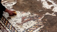 Seorang petugas tampak membersihkan lantai mosaik yang langka ini.
