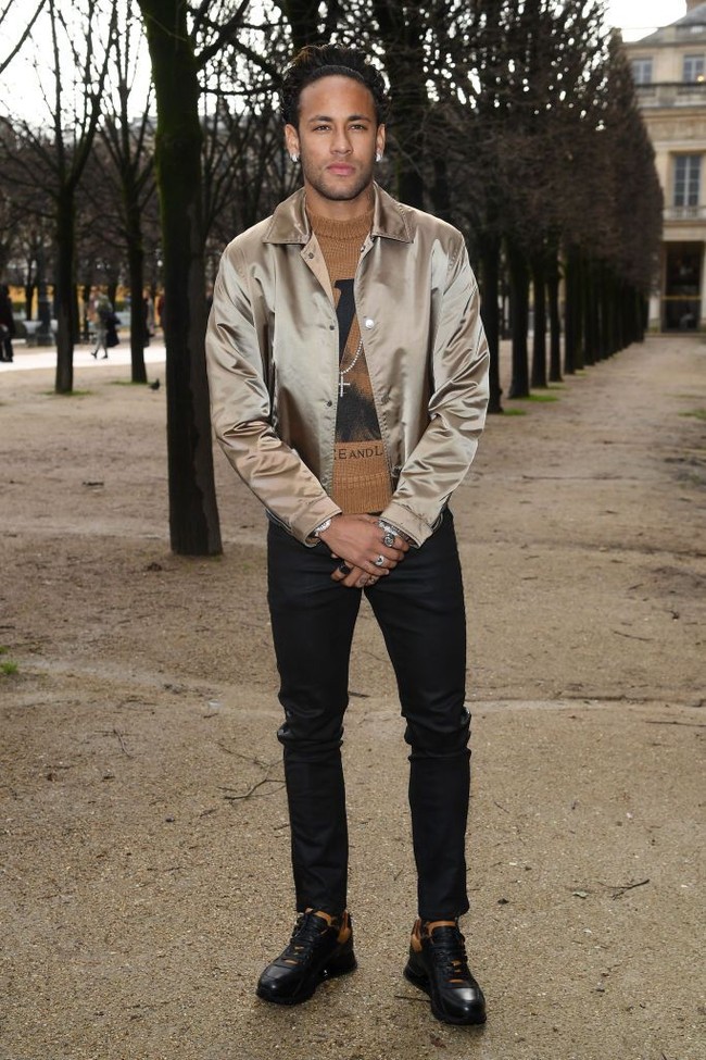 Neymar tampil stylish saat menghadiri fashion show Louis Vuitton Menswear Fall/Winter 2018 di Paris Fahsion Week, 18 Januari 2018. Dia memakai sweater dan jaket cokelat satin dari Louis Vuitton. Foto: Dok. Getty Images.
