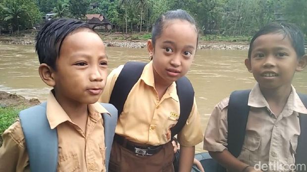 Tak ada ekspresi ketakutan pada 3 bocah ini saat menyeberangi Sungai Oya menggunakan ban. 
