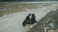 Seorang pria bernama Sumardi (35), warga Dusun Kedungjati memanggul ban karet tidak untuk berenang di sungai, mainkan untuk mengantarkan anak-anak sekolah menyeberangi Sungai Oya untuk berangkat sekolah