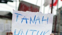 Seorang anak menunjukan poster bertuliskan tanah untuk rakyat