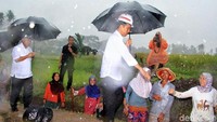Dengan menggunakan payung hitam, Jokowi tetap melangkah ke tengah sawah untuk mengecek proyek pembangunan irigasi yang dibalut Program Padat Karya Tunai yang menjadi andalannya.