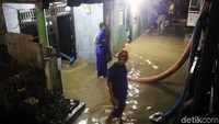 Petugas menyedot air yang merendam rumah warga di Jatinegara, Kamis (8/2).