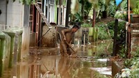 Sampah dan lumpur sisa banjir menutupi jalan di permukiman warga.