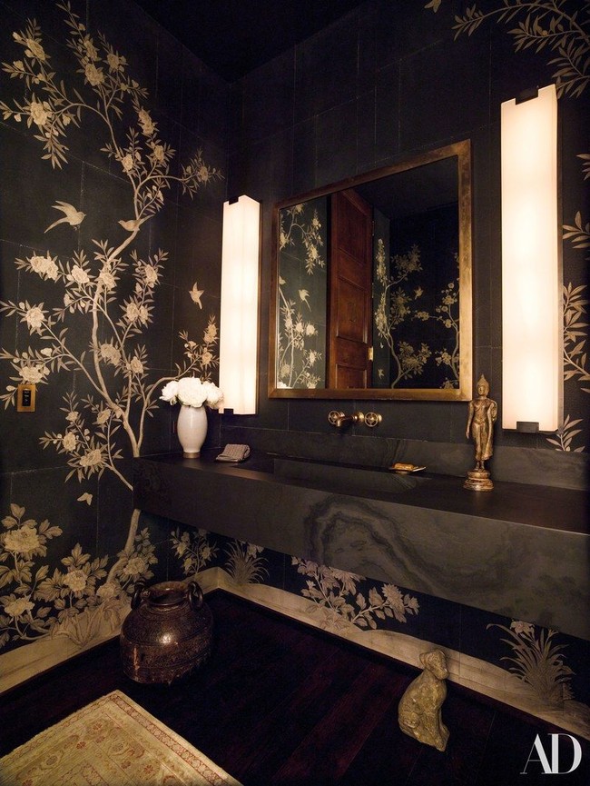 Masuk ke area toilet tamu, muncul kesan dramatis langsung berkat motif floral yang menghiasi dinding keramik berwarna hitam. Foto: Dok. Architectural Digest