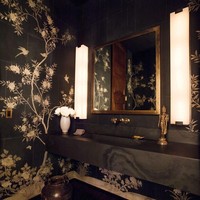 Masuk ke area toilet tamu, muncul kesan dramatis langsung berkat motif floral yang menghiasi dinding keramik berwarna hitam. Foto: Dok. Architectural Digest