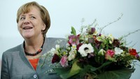 Merkel tampak tersenyum senang saat menerima bunga itu.