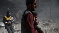Dua pria Suriah tampak menggendong dua bayi untuk menyelamatkan mereka dari gempuran udara rezim Assad di Ghouta Timur. Foto: REUTERS/ Bassam Khabieh