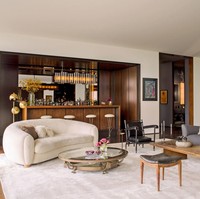 Penampakan ruang keluarga yang dilengkapi sebuah bar. Tampak interior kayu dan tekstur bulu mendominasi, menciptakan kehangatan. Foto: Dok. Architectural Digest