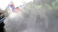 Polisi berusaha memadamkan aksi bakar-bakaran demonnstrasi.