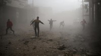 Warga sipil dan anggota pertahanan sipil Ghouta Timur berlari di tengah tebalnya kabut akibat debu reruntuhan, demi menghindari gempuran udara rezim Suriah. Foto: REUTERS/ Bassam Khabieh