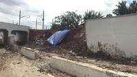 Garis polisi tampak melintang di tengah jalan. Longsoran tanah juga menutupi sebagian badan jalan.
