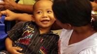 Seorang anak kecil calon penerima bingkisan Imlek itu tampak semringah menemani ibunya menanti angpao.