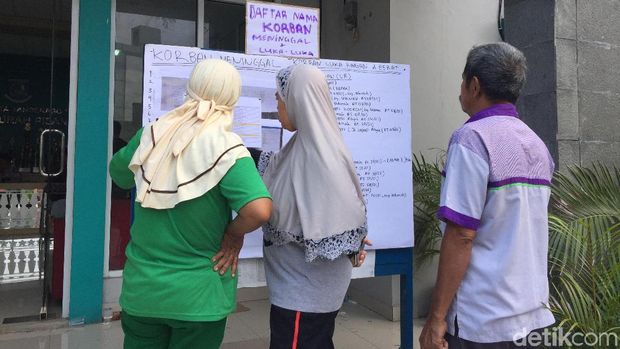 Warga yang membaca papan pengumuman. 