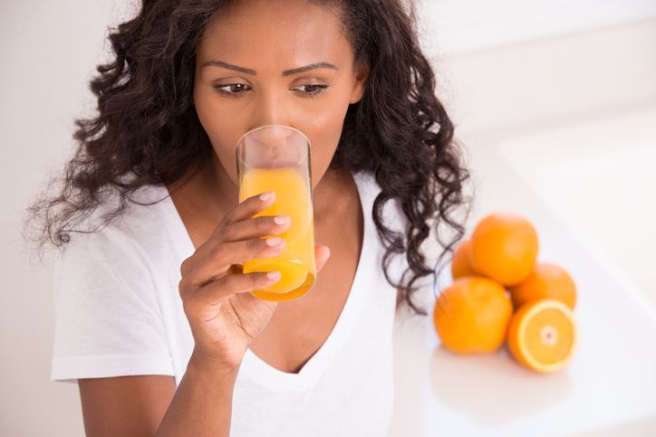 jus jeruk Thirsty woman drinking fresh orange juice at kitchen (high angle view).