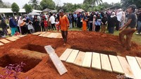 Para pelayat berkerumun di sekitar liang lahat.