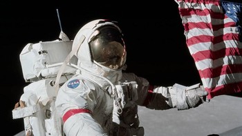 Komandan Apollo 17, astronot Eugene A. Cernan memegang bendera Amerika Serikat saat berhasil mendarat di permukaan Bulan pada 17 Desember 1972. Tampak foto Bumi di kejauhan. Foto: NASA