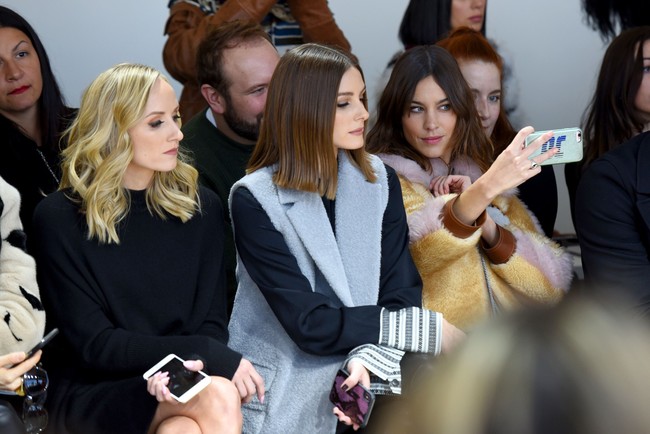 Aktris dan model Alexa Chung sibuk berswafoto, sementara sosialita Olivia Palermo fokus memperhatikan koleksi Noon by Noor, Kamis (8/2/2018). (Foto: Getty Images)
