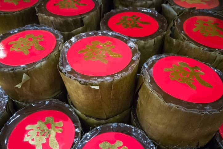 Nian Gao disajikan di meja dengan segelas cupcakes jus jeruk dan bungkusan merah.  gambarnya sangat cocok untuk artikel makanan dan minuman serta semua desain yang berkaitan dengan perayaan Tahun Baru Imlek