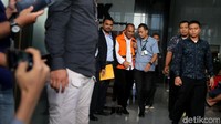 Marianus resmi mengenakan rompi tahanan warna oranye khas KPK. Dia kemudian dikawal menuju ke mobil tahanan.