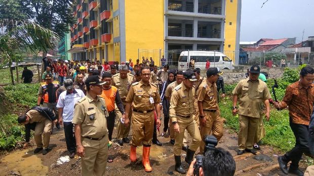 Anies dan Bima mengganti sepatu pantofel yang mereka kenakan dengan sepatu boots. 