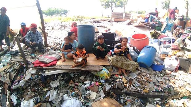 Warga yang rumahnya digusur duduk di atas puing bangunan yang ditertibkan