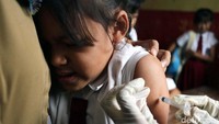 Seorang anak tampak meringis kesakitan saat jarum suntik menembus kulitnya.