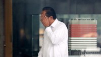 Agus Wahjudo menutupi wajahnya dari sorotan kamera wartawan.