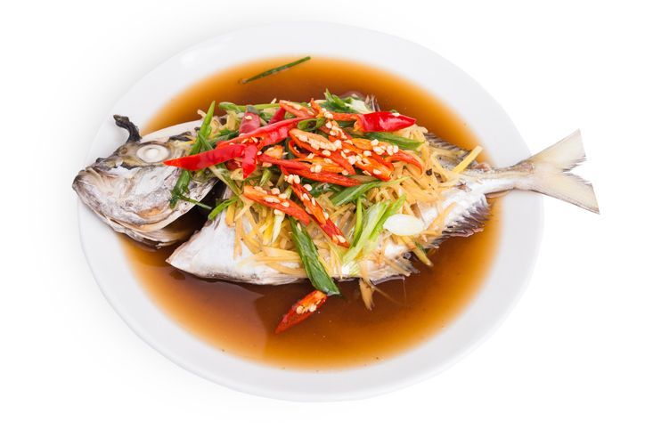 Chinese Food whole fish steamed with ginger, scallion and soy sauce, served on a platter with head and tail complete.
