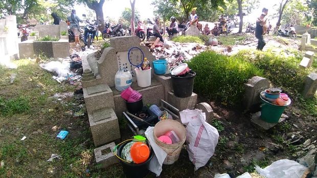 Warga meletakkan barangnya di antara makam