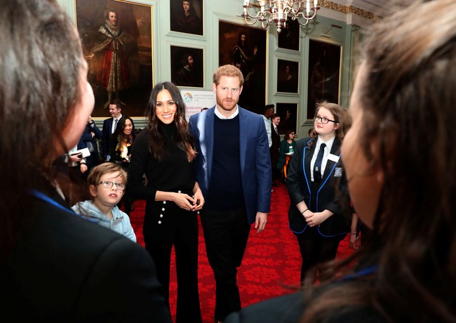 Di dalam ruangan, Meghan terlihat mengenakan busana serba hitam dengan wide-pants beraksen kancing emas pada kantong. Foto: Reuters
