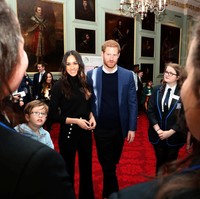 Di dalam ruangan, Meghan terlihat mengenakan busana serba hitam dengan wide-pants beraksen kancing emas pada kantong. Foto: Reuters