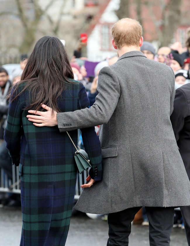 Pangeran Harry menunjukkan sisi protektifnya dengan merangkul Meghan Markle dari belakang. Foto: Getty Images
