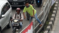 Salah seorang warga memanjat pagar pembatas yang sangat tinggi untuk mengambil jalan pintas, di Jalan Jatinegara, Jakarta Timur, Rabu (14/2).