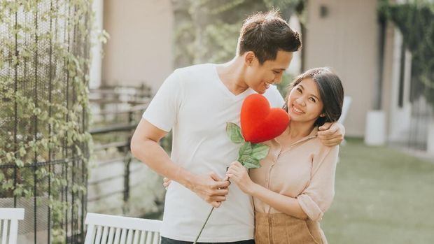 Romantic happy Asian couple in love having fun with heart flower while hugging. Vanlentine day concept.