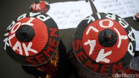 Dalam aksinya, mereka membantangkan spanduk dan memakai caping.