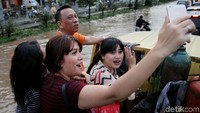 Bahkan ada warga yang sempat swafoto bersama di tengah banjir saat menumpang kendaraan bak terbuka.